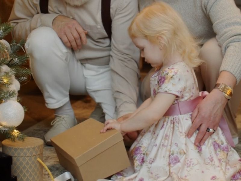 devojčica sa raditeljima kiti jelku i otvara poklon