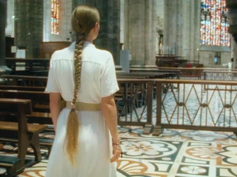 devojka u elegantnoj beloj haljini sa kaišem oko struka šeta po crkvi