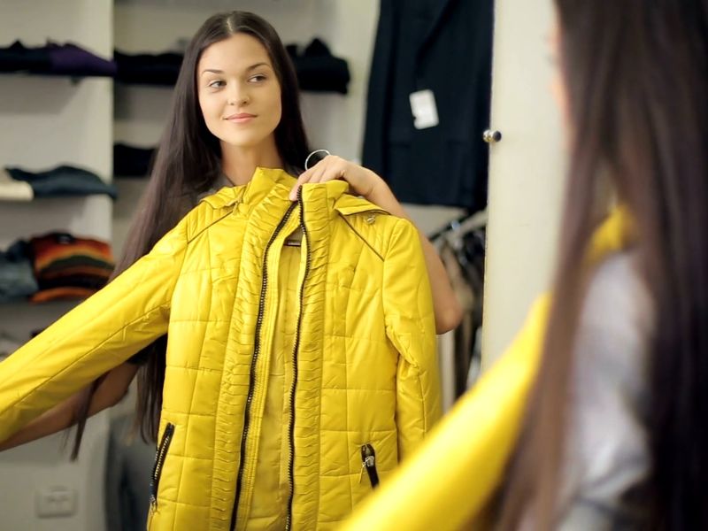 prikaz devojke koja je prislonila jaknu na sebe žute boje i gleda kako joj stoji