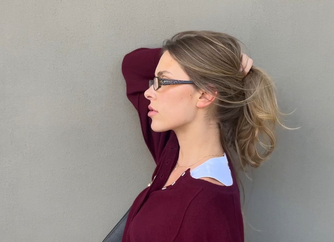 devojka u bordo džemperu sa naočarama na glavi pozira