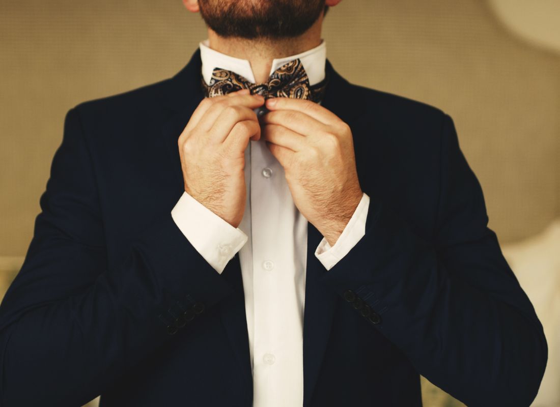 prikaz momka u odelu koji stavlja sebi leptir mašnu